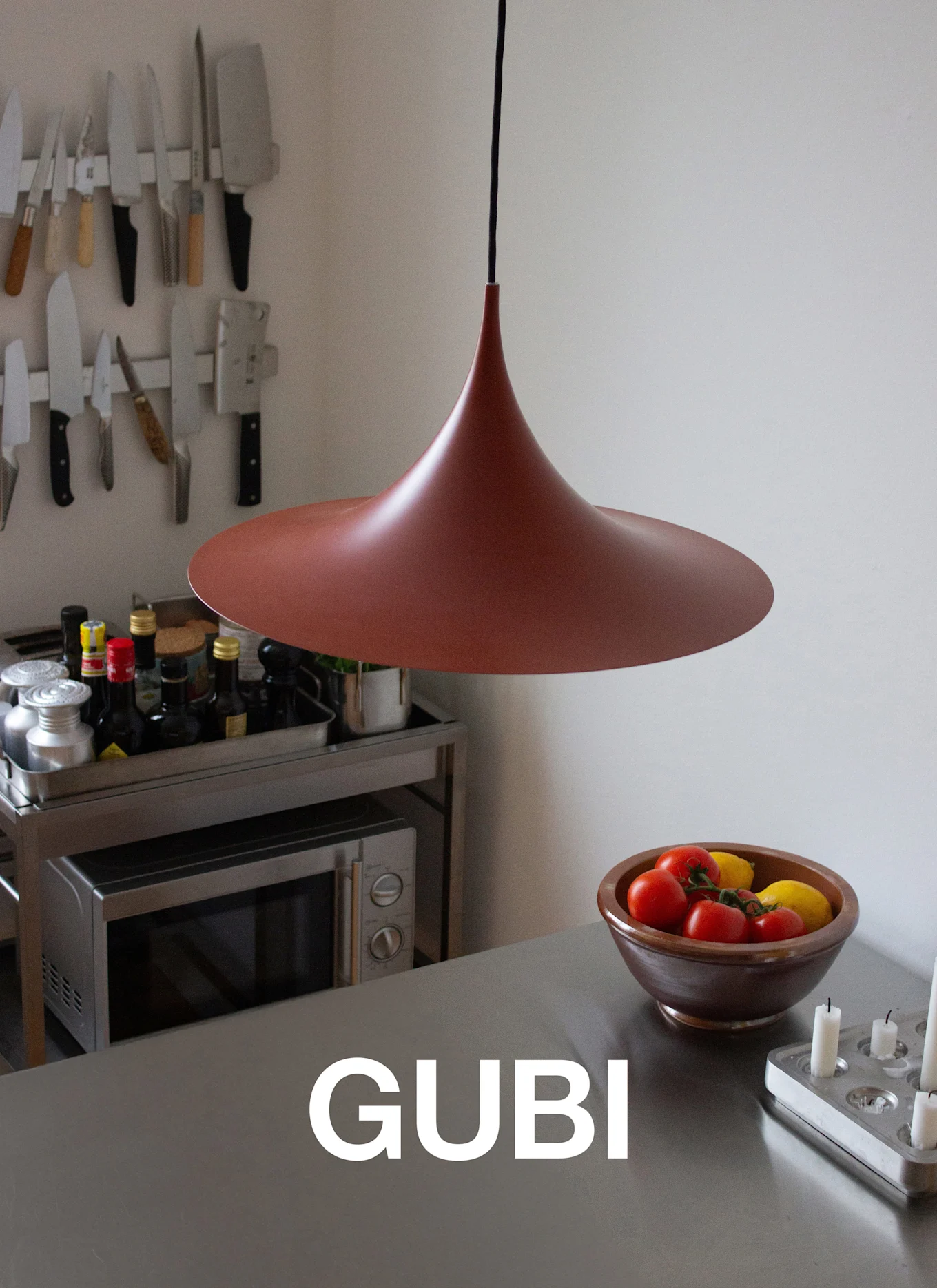 Et uregelmessig svart salongbord med tynne ben på et lilla teppe, med en bok og glasskopp, ved en hvit peis.