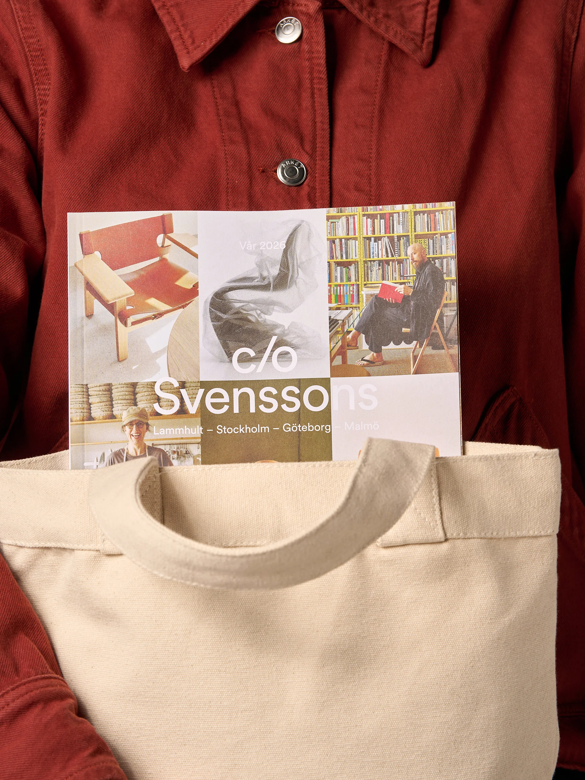 En person i rød jakke holder en beige stoffveske med et "Svenssons"-magasin som stikker opp. Forsiden viser møbler og mennesker.