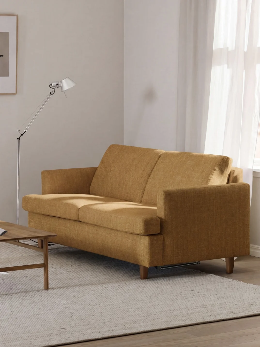 Sennepsgul sofa i en lys stue med et trebord, et bilde på veggen og et vindu med hvite gardiner.